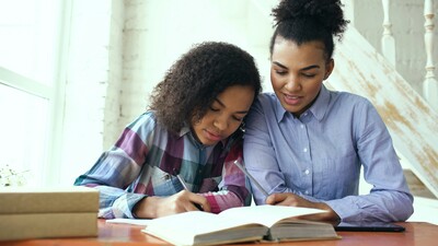     Mother and school-age child working together at a desk during a literacy therapy session. 