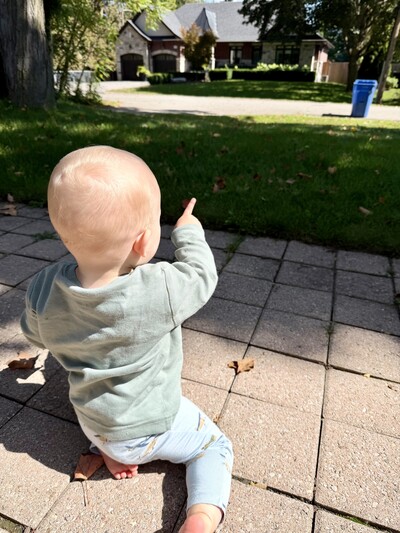 Infant pointing at the grass during an outdoor speech therapy session.  